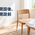窓辺の明るい部屋に置かれた木の椅子と、小さなテーブルの上の書類